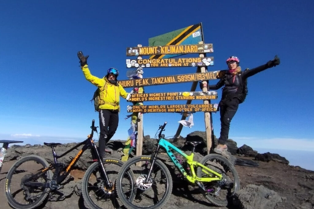 Two mountain bikers at the summit of Mount Kilimanjaro