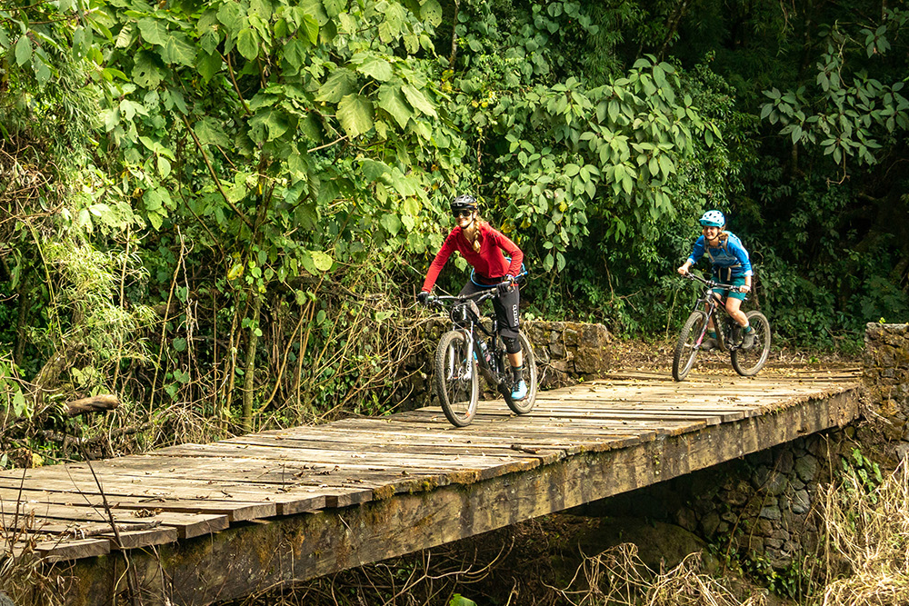 Mountain bikers riding across a wooden bridge in Guatemala