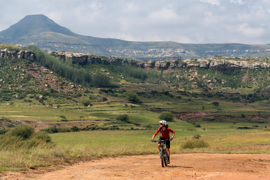 A mountain biker in Lesotho riding on a dirt road with beautiful scenery in the background