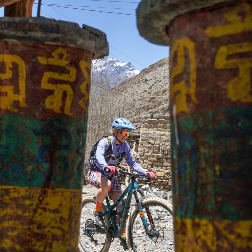 A mountain biker in Nepal framed between two bells