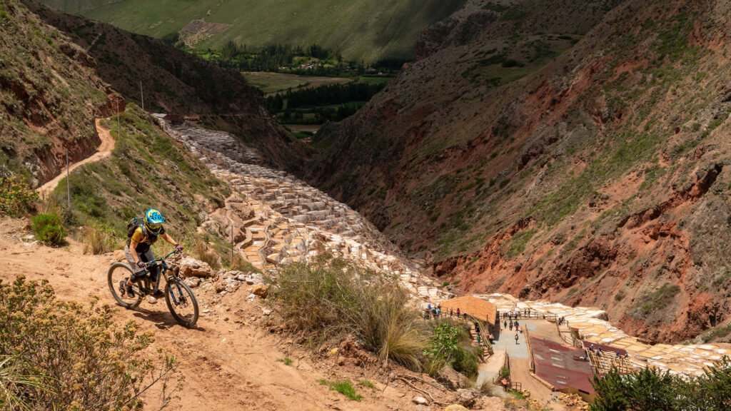 A mountain biker riding high above the salt mine pools in the Sacred Valley of Peru