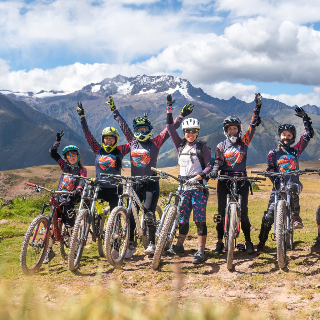 A group of riders posing in front of the Andes with their arms raised