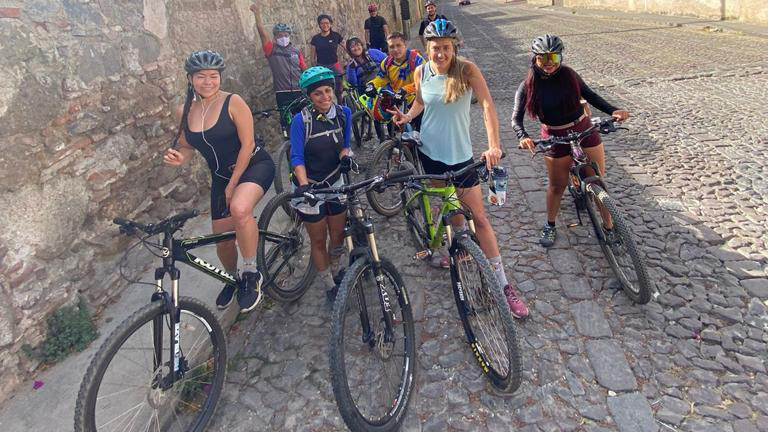 World Ride ambassadors sit on their bikes on a cobbled street